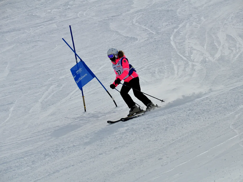Skifahrerin in rosa Hose zieht eine Kurve am blauen Tor.